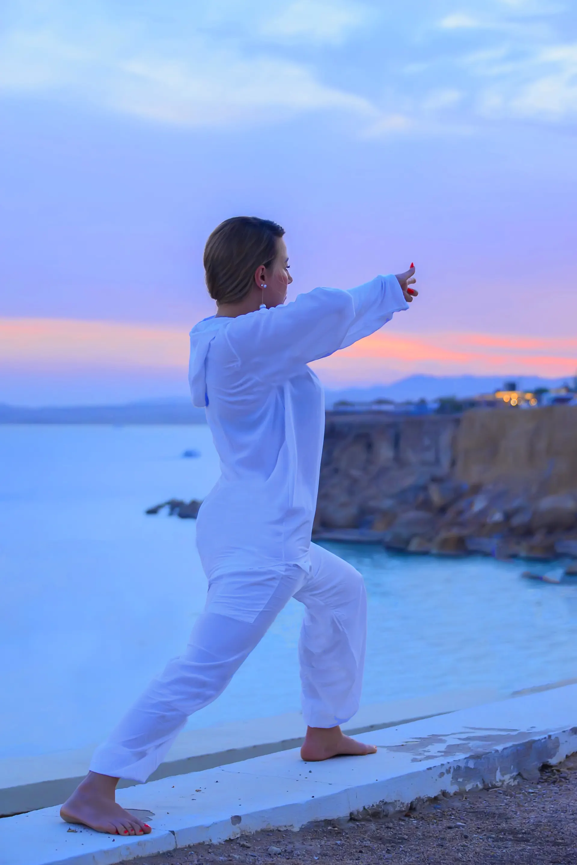 Ilaria Sorbo — posture yoga debout face à la mer, coucher de soleil